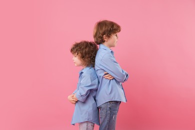 Photo of Cute little brothers back to back on pink background