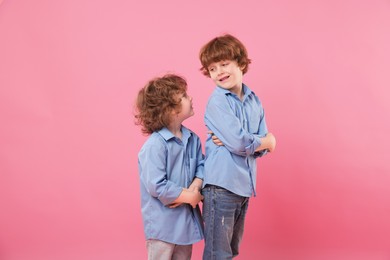 Photo of Cute little brothers together on pink background