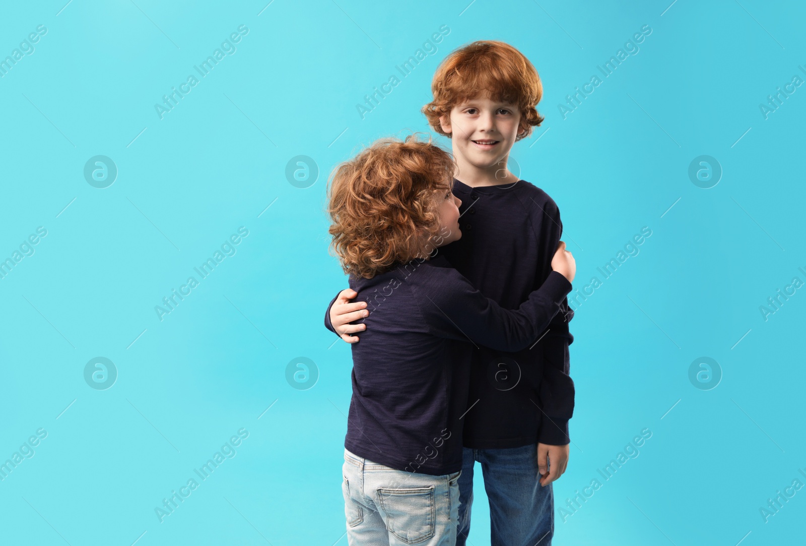 Cute little brothers hugging on light blue background. Space for text Photo of Cute little brothers hugging on light blue background. Space for text