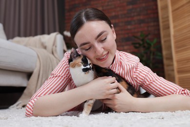Photo of Woman with her cute calico kitten on floor at home
