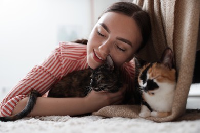 Photo of Woman with her cute calico kittens on floor at home