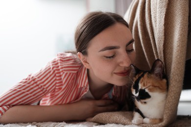 Photo of Woman with her cute calico kitten on floor at home