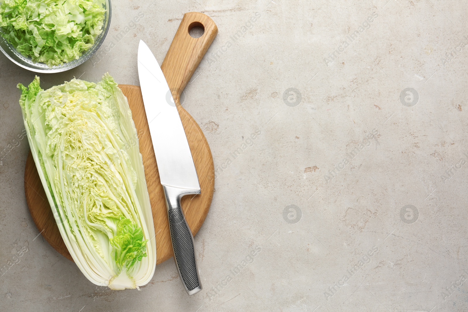 Cut Chinese cabbage and knife on light grey table, top view. Space for text Photo of Cut Chinese cabbage and knife on light grey table, top view. Space for text