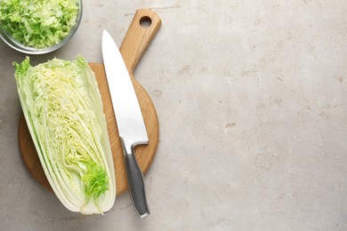 Photo of Cut Chinese cabbage and knife on light grey table, top view. Space for text