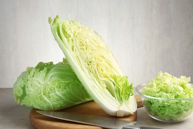 Photo of Fresh Chinese cabbages and knife on light grey table, closeup