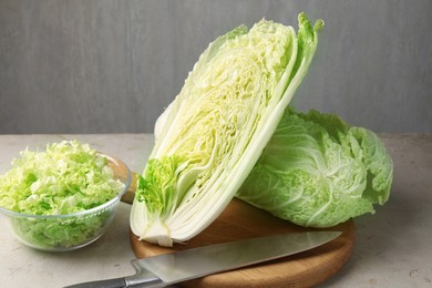Photo of Fresh Chinese cabbages and knife on light grey table, closeup