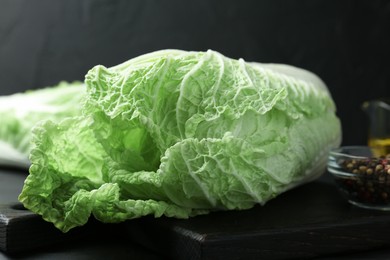 Photo of Fresh Chinese cabbages and peppercorns on black wooden table, closeup
