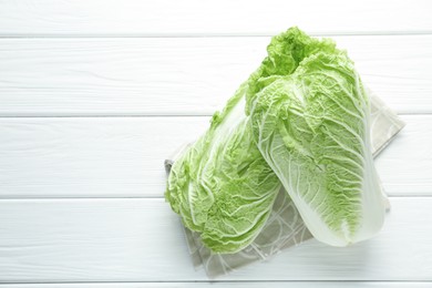 Photo of Fresh Chinese cabbages on white wooden table, top view. Space for text