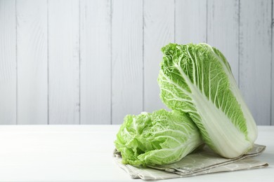 Photo of Fresh Chinese cabbages on white wooden table, space for text