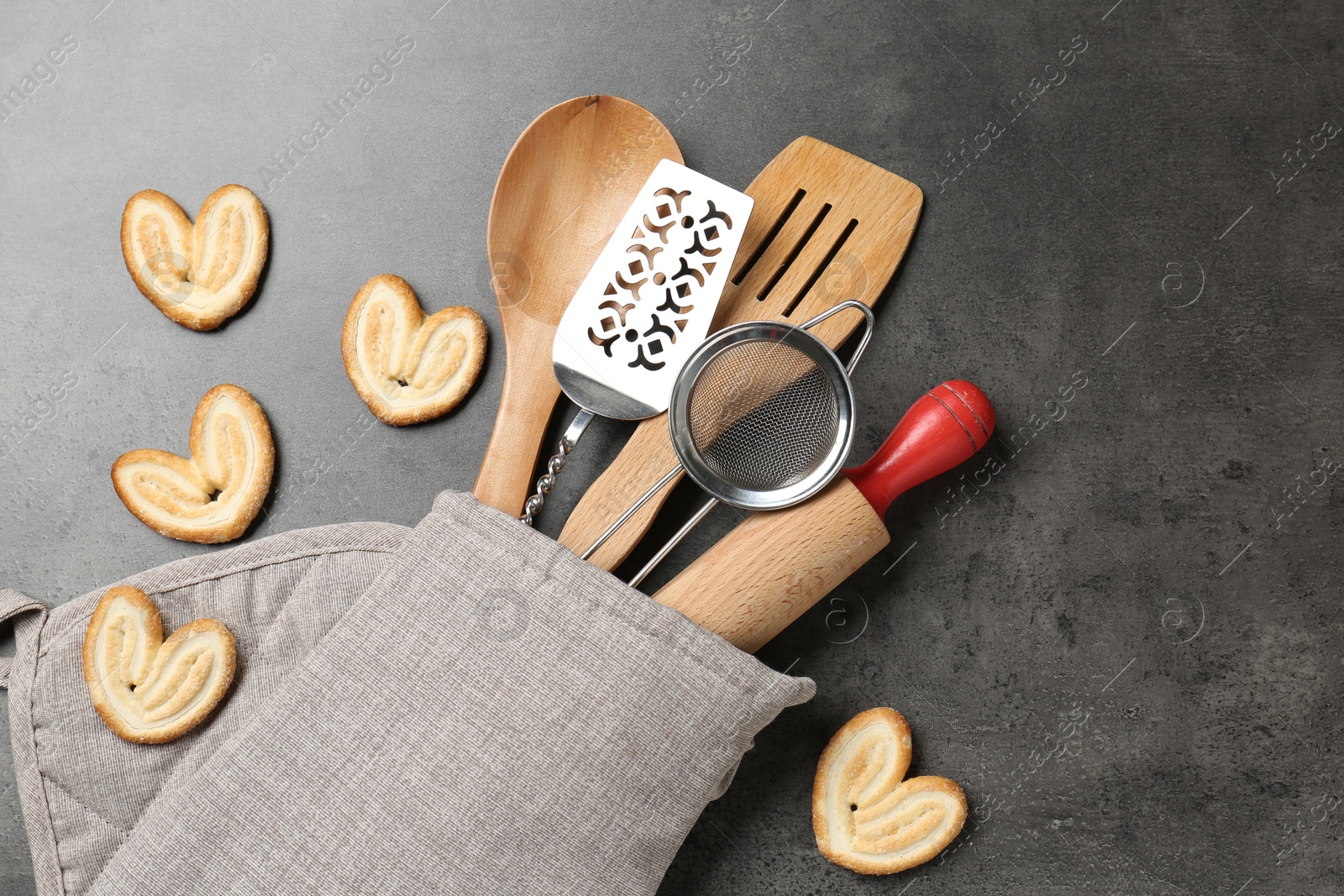 Different kitchen utensils in oven mitten and cookies on grey table, flat lay Photo of Different kitchen utensils in oven mitten and cookies on grey table, flat lay