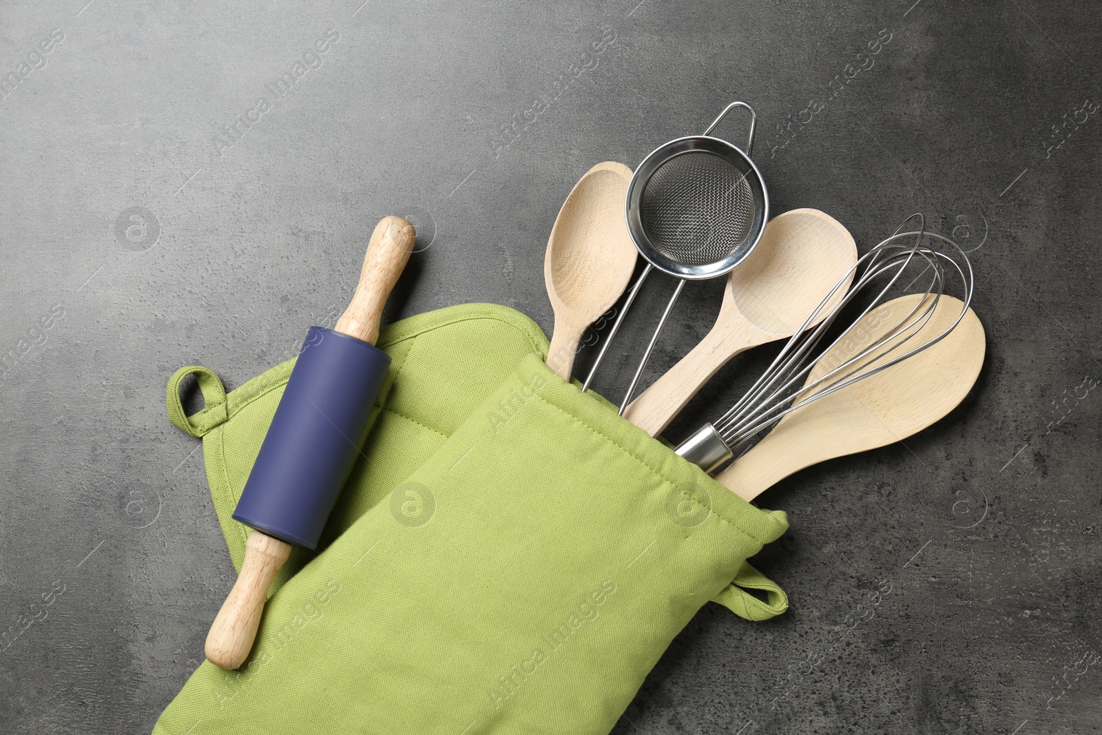 Different kitchen utensils in oven mitten on grey table, flat lay Photo of Different kitchen utensils in oven mitten on grey table, flat lay