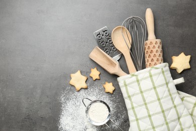 Photo of Different kitchen utensils in oven mitten, flour and cookies on grey table, flat lay. Space for text