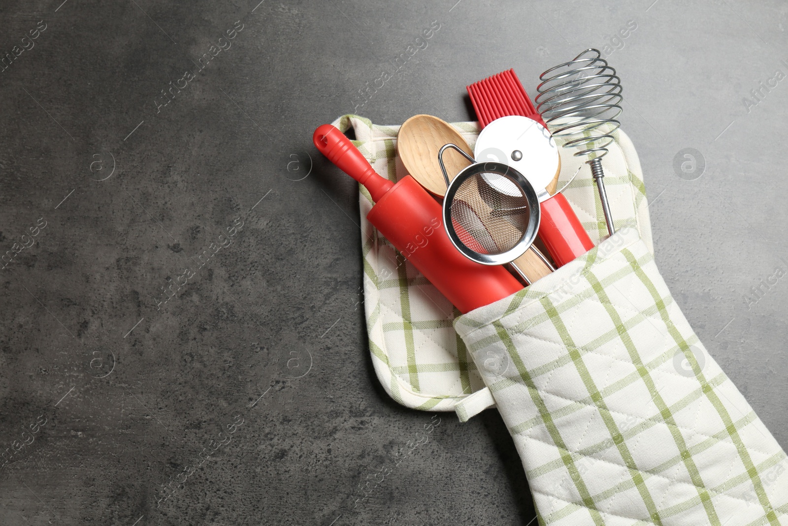 Different kitchen utensils in oven mitten on grey table, top view. Space for text Photo of Different kitchen utensils in oven mitten on grey table, top view. Space for text