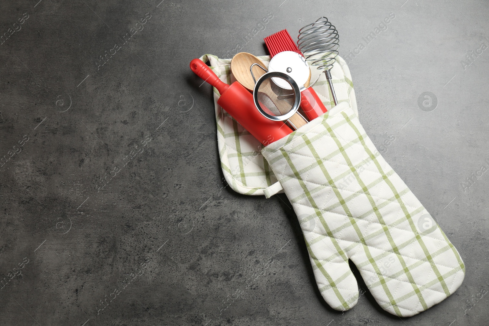 Different kitchen utensils in oven mitten on grey table, top view. Space for text Photo of Different kitchen utensils in oven mitten on grey table, top view. Space for text