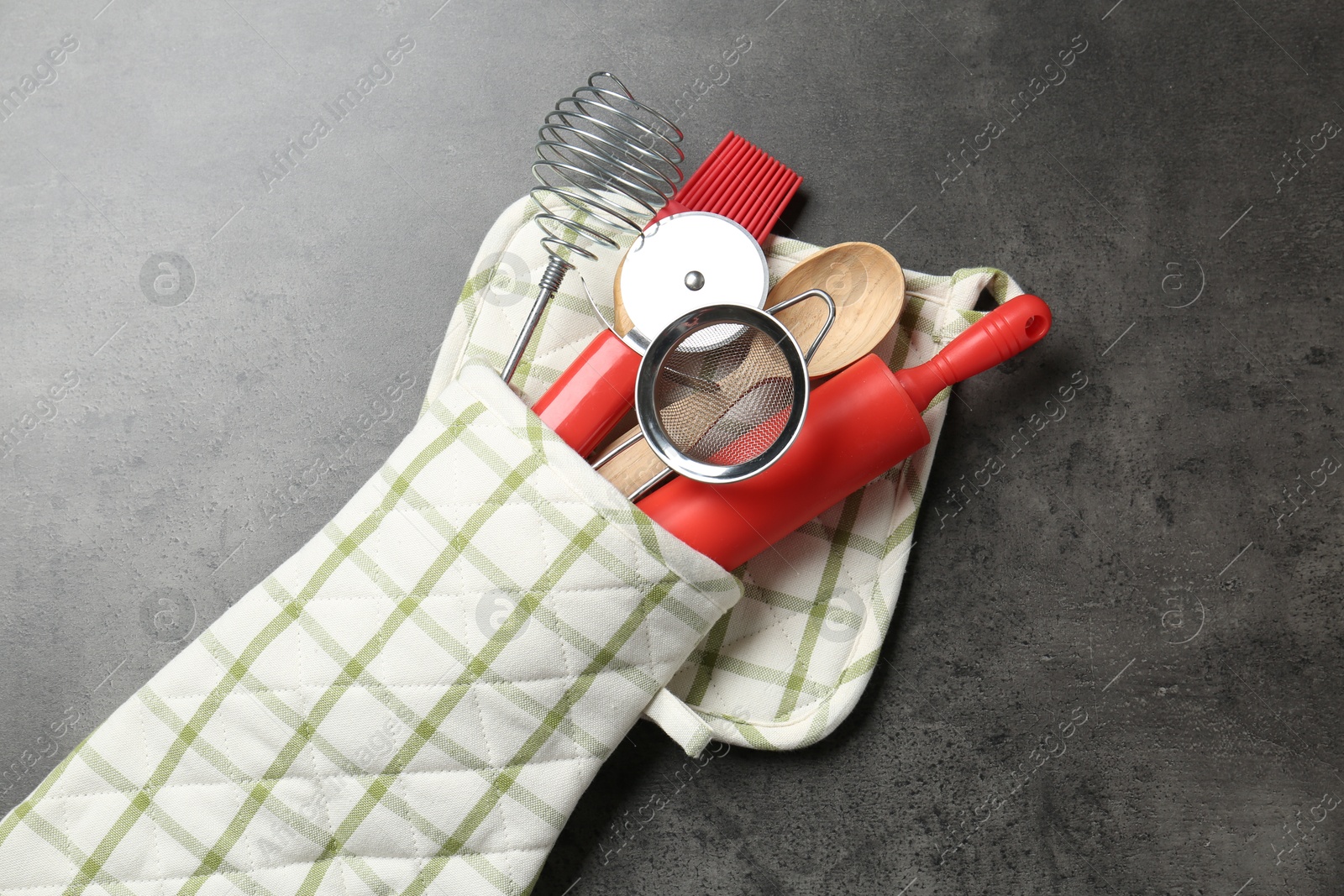 Different kitchen utensils in oven mitten on grey table, top view Photo of Different kitchen utensils in oven mitten on grey table, top view