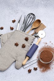 Photo of Different kitchen utensils in oven mitten, cocoa powder and anise stars on light table, flat lay