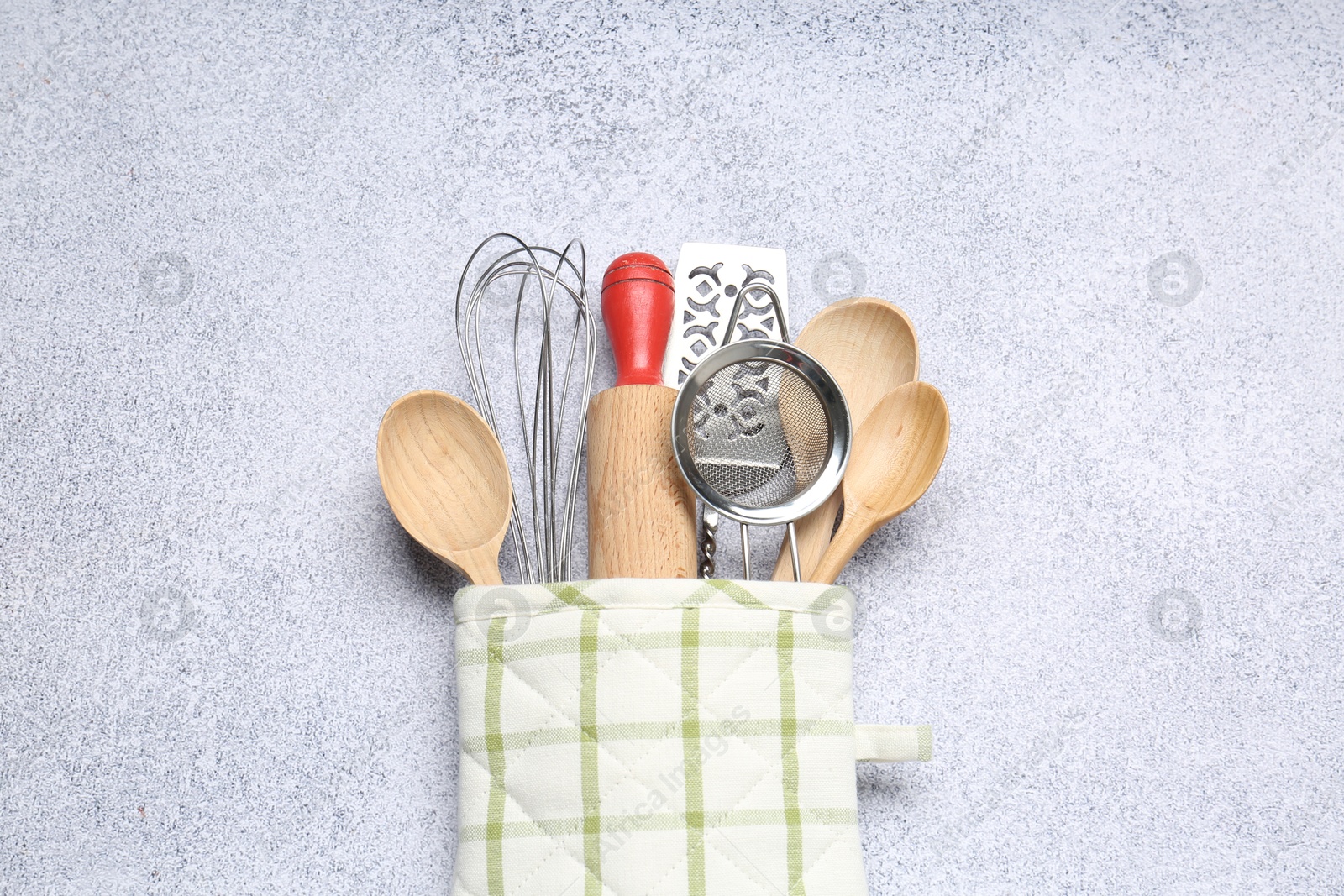 Different kitchen utensils in oven mitten on light table, top view Photo of Different kitchen utensils in oven mitten on light table, top view