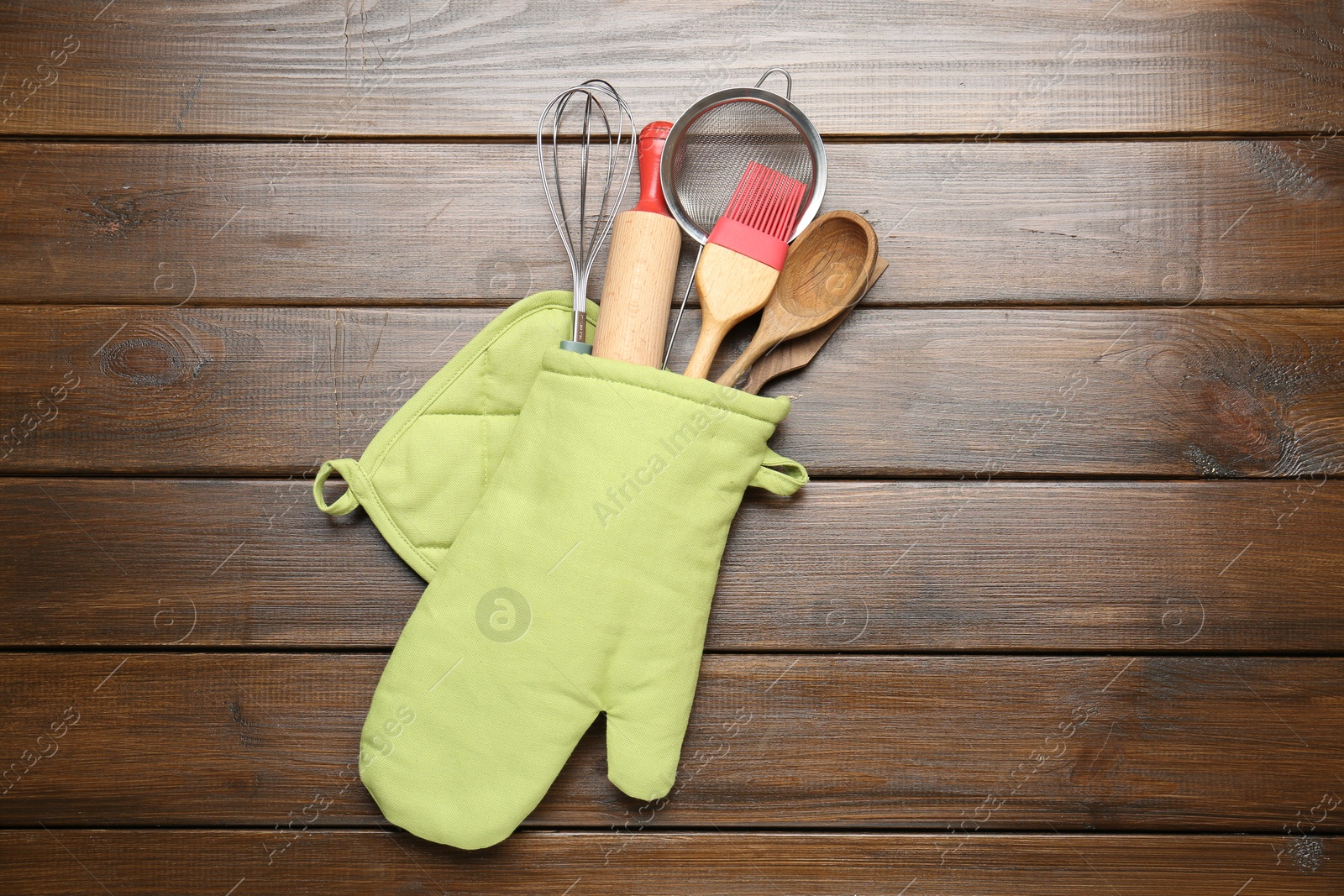 Different kitchen utensils in oven mitten on wooden table, top view Photo of Different kitchen utensils in oven mitten on wooden table, top view