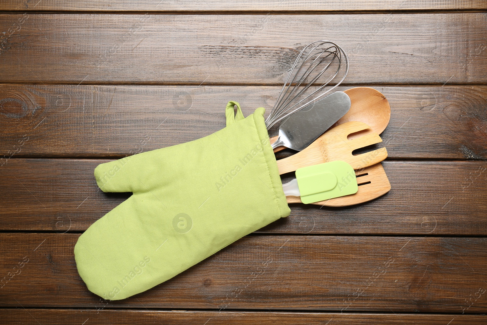 Different kitchen utensils in oven mitten on wooden table, top view Photo of Different kitchen utensils in oven mitten on wooden table, top view