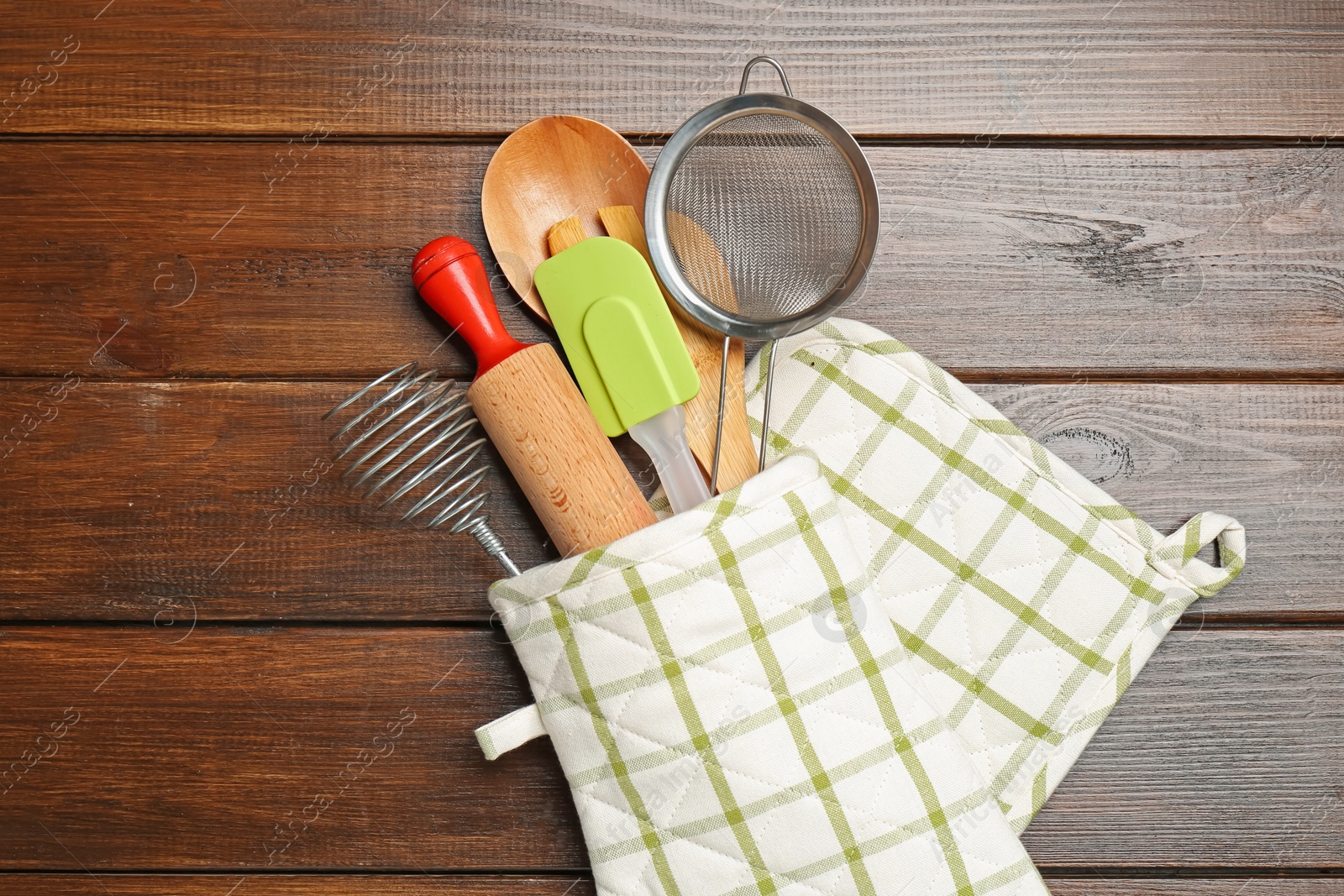Different kitchen utensils in oven mitten on wooden table, top view Photo of Different kitchen utensils in oven mitten on wooden table, top view