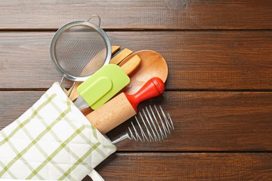 Photo of Different kitchen utensils in oven mitten on wooden table, top view. Space for text