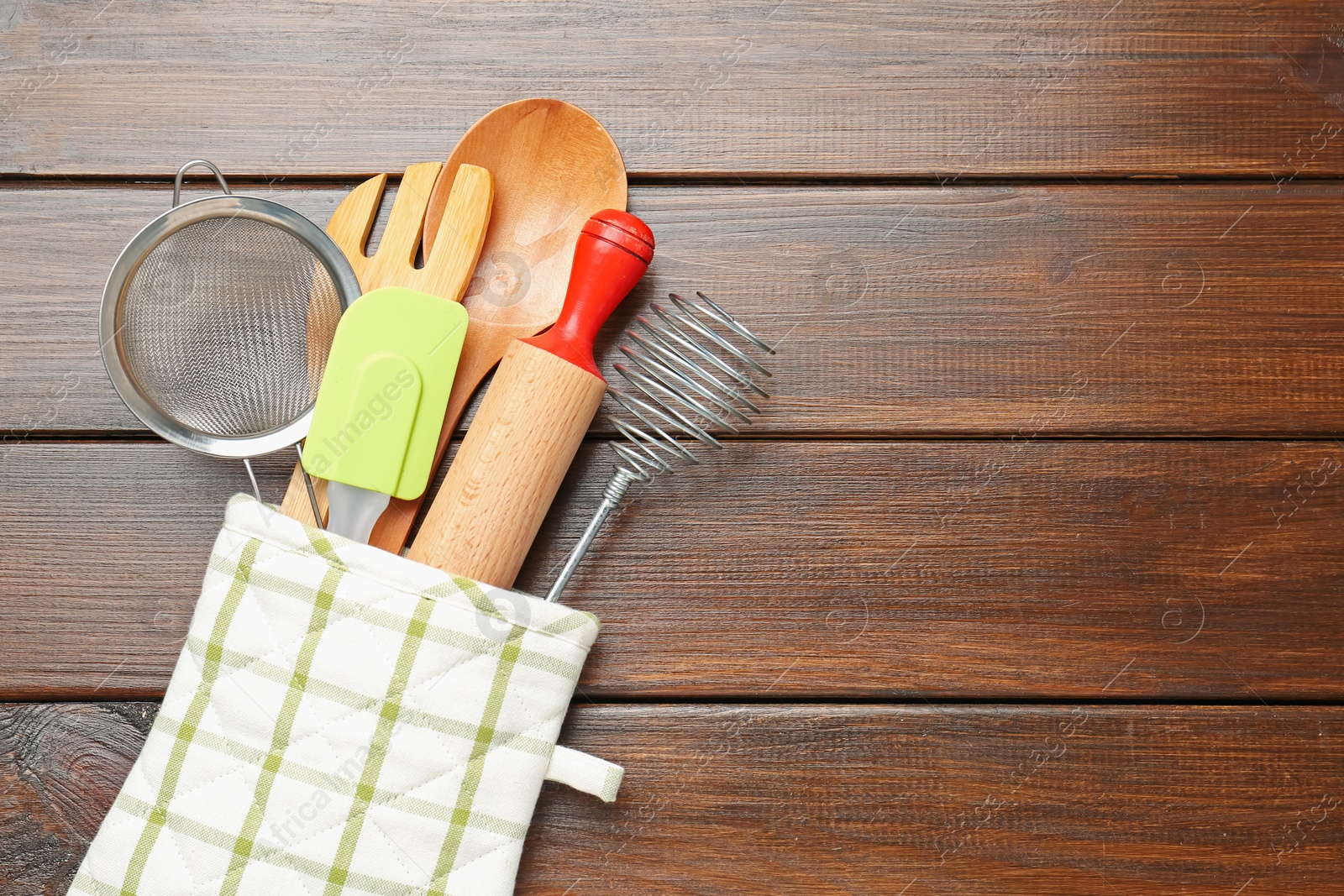 Different kitchen utensils in oven mitten on wooden table, top view. Space for text Photo of Different kitchen utensils in oven mitten on wooden table, top view. Space for text