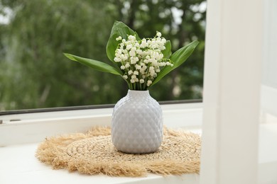 Photo of Bouquet of lily-of-the-valley flowers in vase on windowsill indoors
