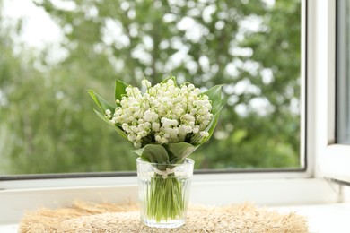 Photo of Bouquet of lily-of-the-valley flowers in vase on windowsill indoors