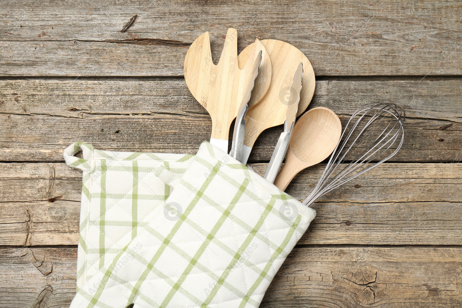 Different kitchen utensils in oven mitten on wooden table, top view Photo of Different kitchen utensils in oven mitten on wooden table, top view