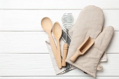 Photo of Different kitchen utensils and oven mitten on white wooden table, top view. Space for text