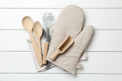 Photo of Different kitchen utensils and oven mitten on white wooden table, top view