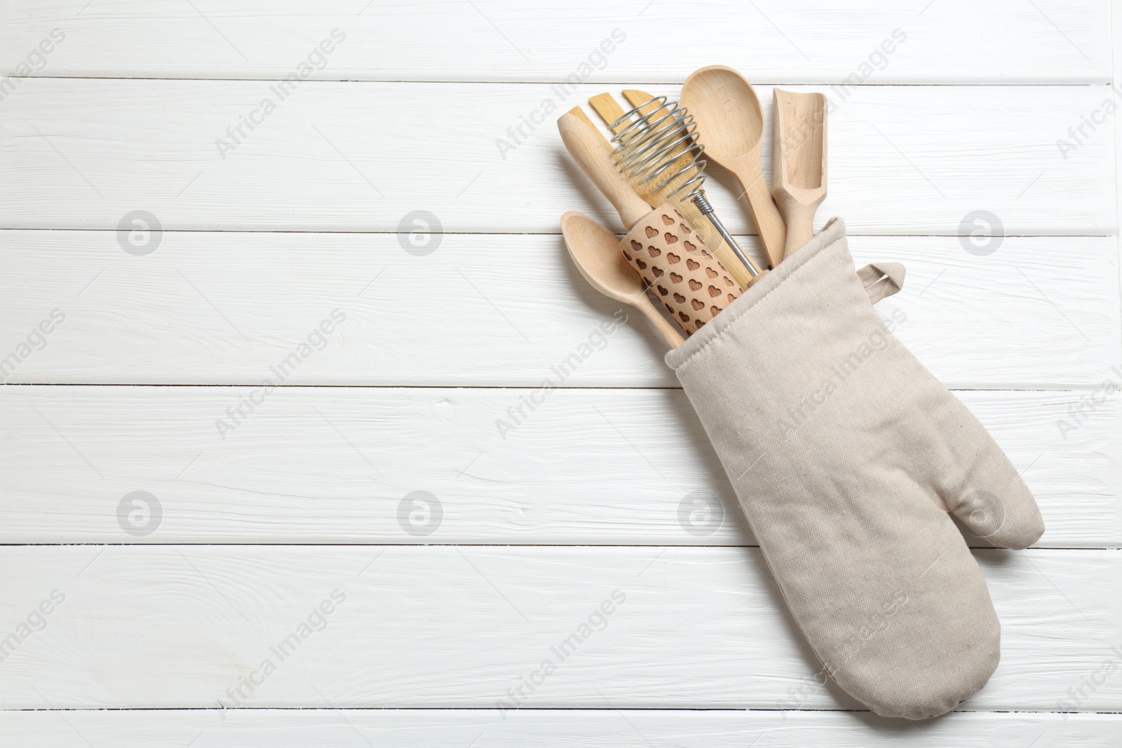 Different kitchen utensils in oven mitten on white wooden table, top view. Space for text Photo of Different kitchen utensils in oven mitten on white wooden table, top view. Space for text