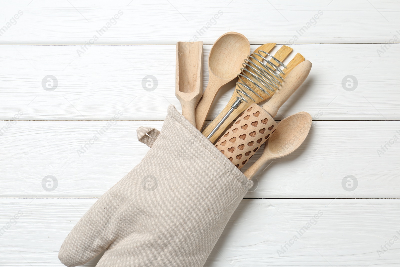 Different kitchen utensils in oven mitten on white wooden table, top view Photo of Different kitchen utensils in oven mitten on white wooden table, top view