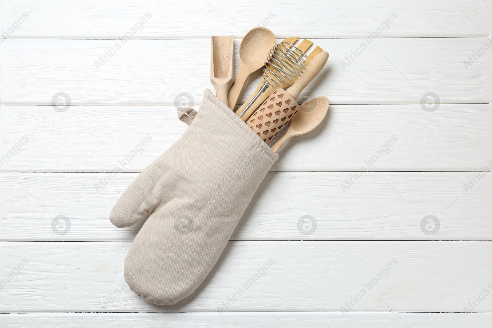 Different kitchen utensils in oven mitten on white wooden table, top view Photo of Different kitchen utensils in oven mitten on white wooden table, top view