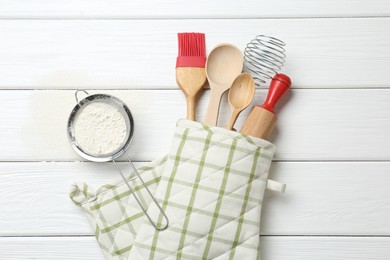 Photo of Different kitchen utensils in oven mitten and flour on white wooden table, flat lay