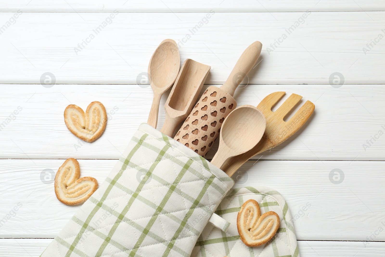 Different kitchen utensils in oven mitten and palmier cookies on white wooden table, flat lay Photo of Different kitchen utensils in oven mitten and palmier cookies on white wooden table, flat lay