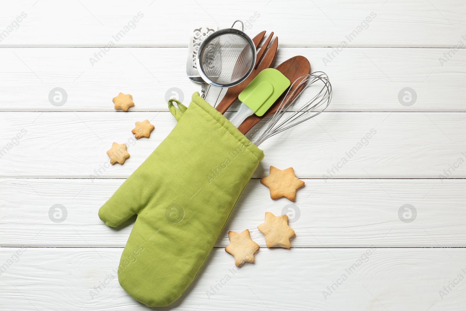 Different kitchen utensils in oven mitten and star shaped cookies on white wooden table, flat lay Photo of Different kitchen utensils in oven mitten and star shaped cookies on white wooden table, flat lay