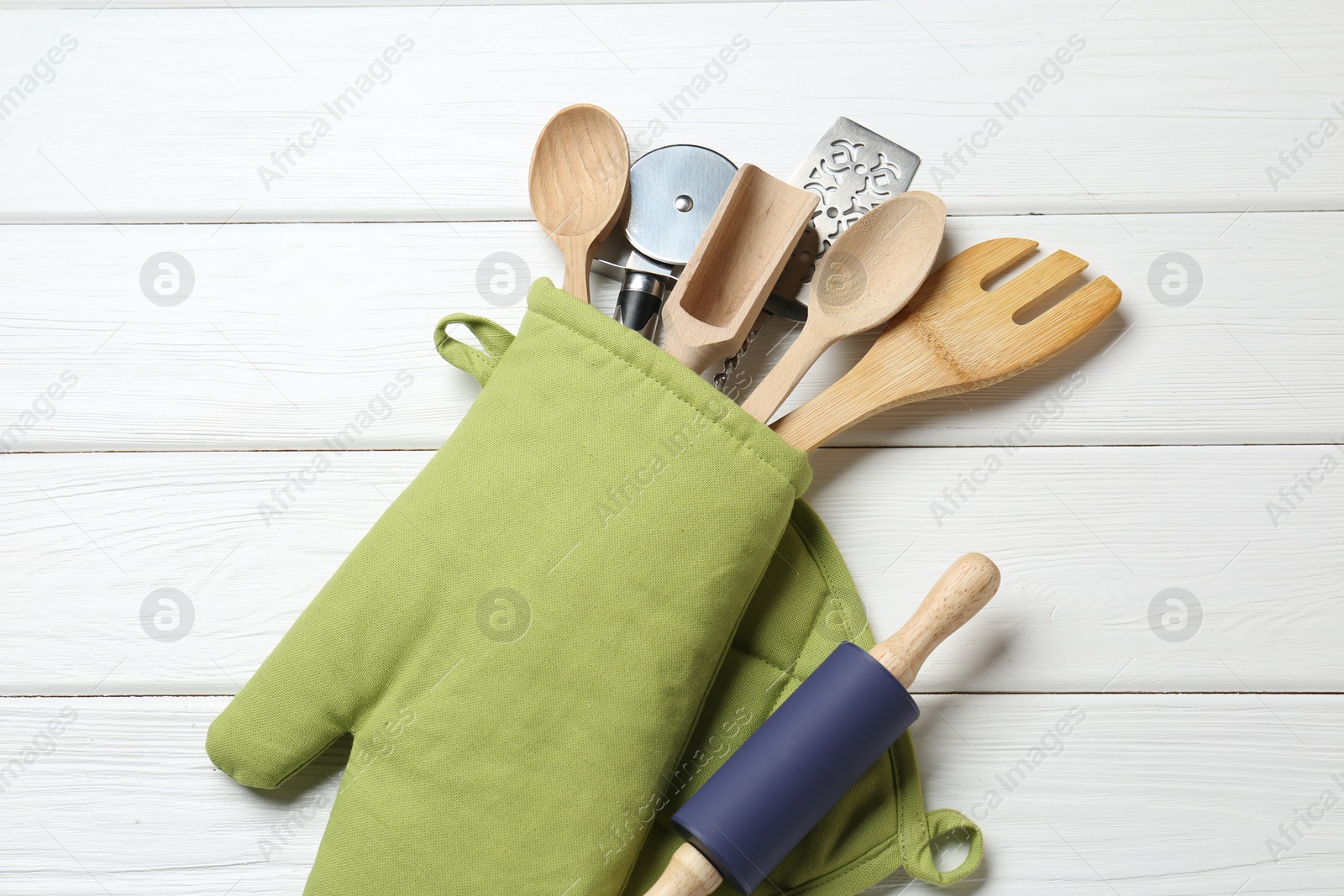 Different kitchen utensils in oven mitten on white wooden table, top view Photo of Different kitchen utensils in oven mitten on white wooden table, top view