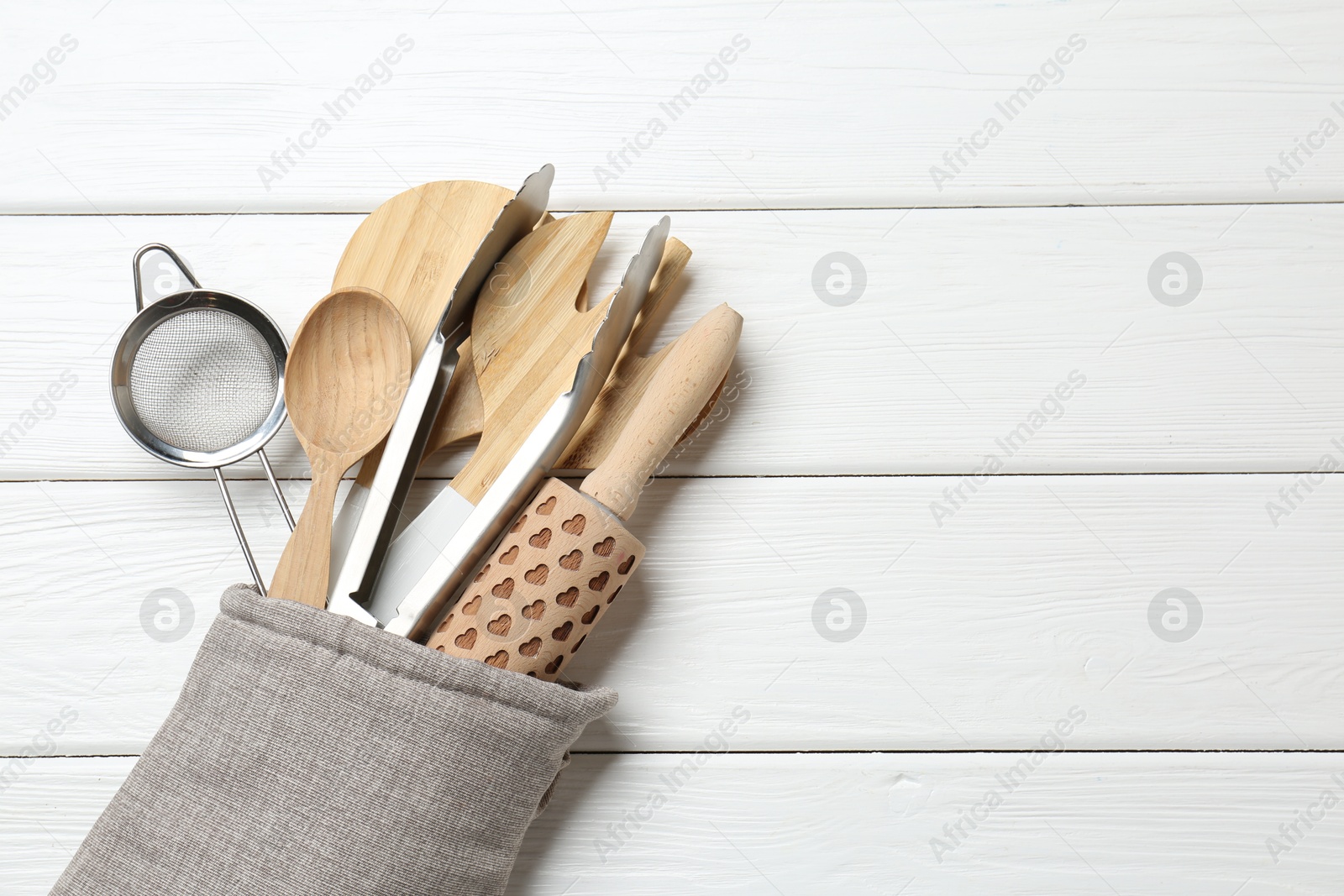 Different kitchen utensils in oven mitten on white wooden table, top view. Space for text Photo of Different kitchen utensils in oven mitten on white wooden table, top view. Space for text