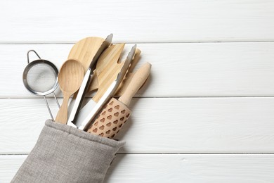 Photo of Different kitchen utensils in oven mitten on white wooden table, top view. Space for text