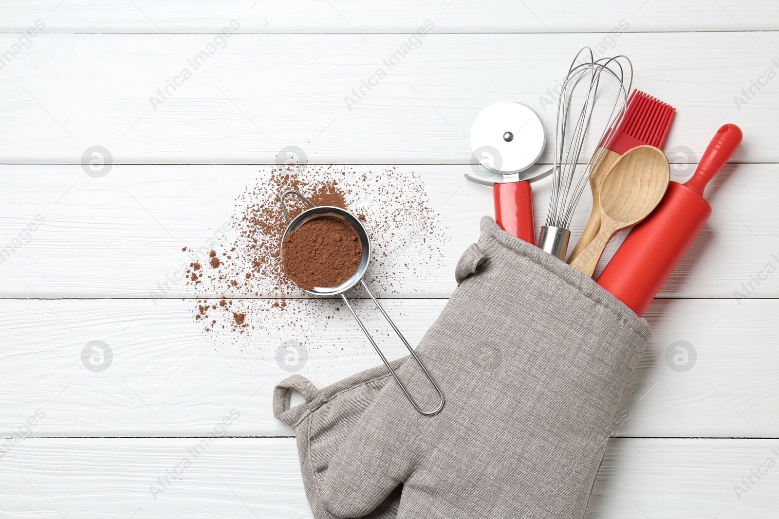 Different kitchen utensils in oven mitten and cinnamon on white wooden table, flat lay. Space for text Photo of Different kitchen utensils in oven mitten and cinnamon on white wooden table, flat lay. Space for text