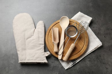 Photo of Different kitchen utensils and oven mitten on grey table, flat lay