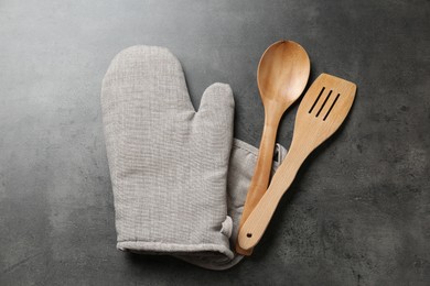 Photo of Spoon, spatula and oven mitten on grey table, flat lay