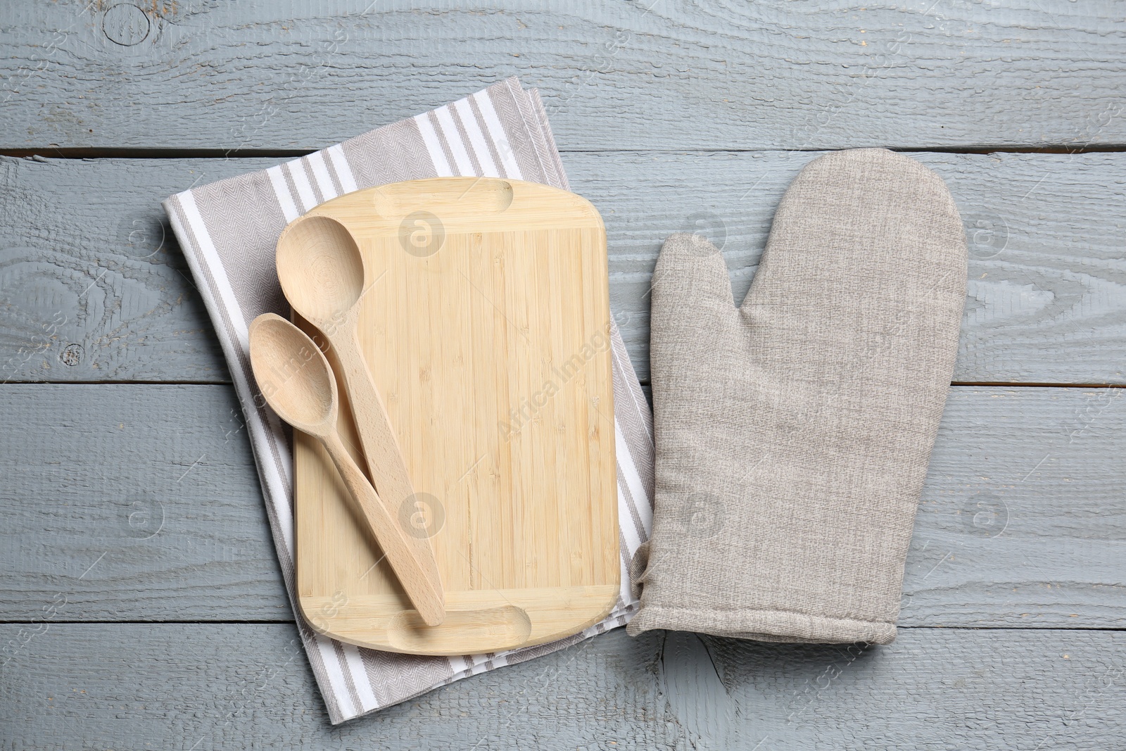 Different kitchen utensils and oven mitten on light grey wooden table, flat lay Photo of Different kitchen utensils and oven mitten on light grey wooden table, flat lay