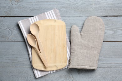 Photo of Different kitchen utensils and oven mitten on light grey wooden table, flat lay
