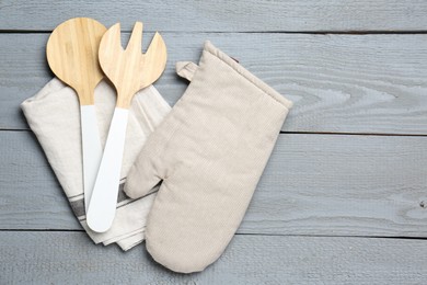 Photo of Kitchen utensils and oven mitten on light grey wooden table, top view. Space for text