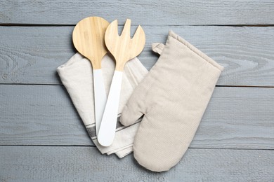 Photo of Kitchen utensils and oven mitten on light grey wooden table, top view