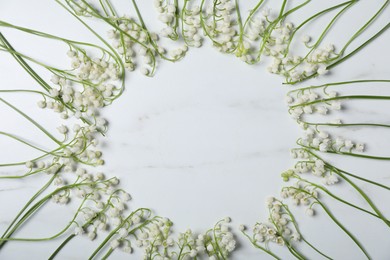 Photo of Frame of beautiful lily-of-the-valley flowers on white marble background, flat lay. Space for text
