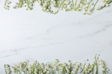 Photo of Beautiful lily-of-the-valley flowers on white marble background, flat lay. Space for text