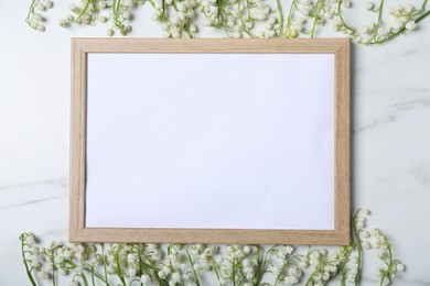 Photo of Beautiful lily-of-the-valley flowers and blank frame on white marble background, flat lay. Space for text